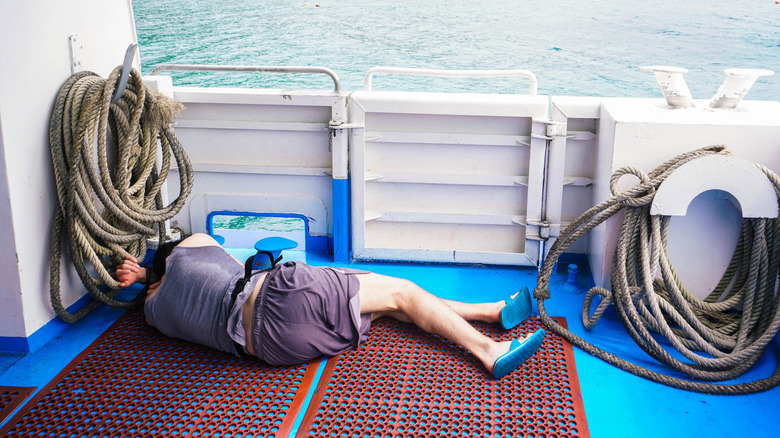 Man laying with his back to the camera on the deck of a cruise ship