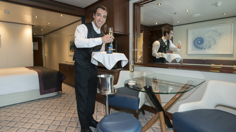 A room service steward on board Seabourn Encore delivers champagne to a cabin