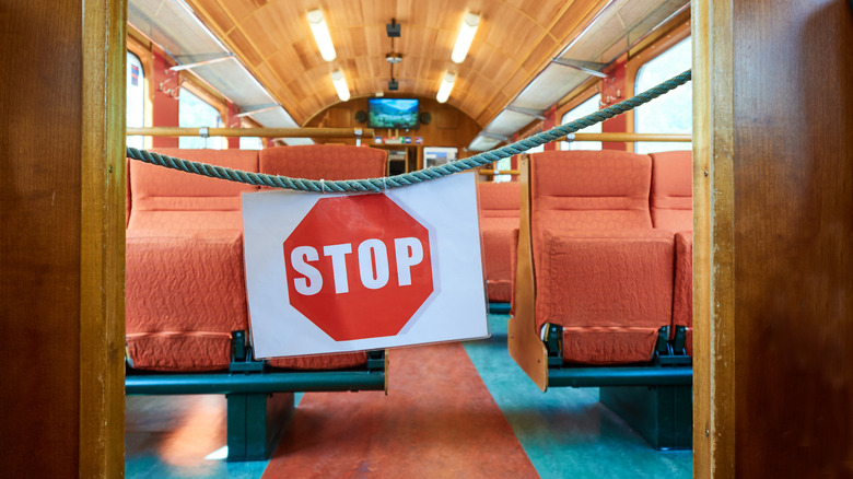 Stop sign hanging across the entry to a car on a passenger train, halting traveler access
