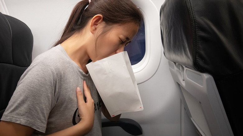 A female passenger on the plane affected with nausea and using the sick bag.