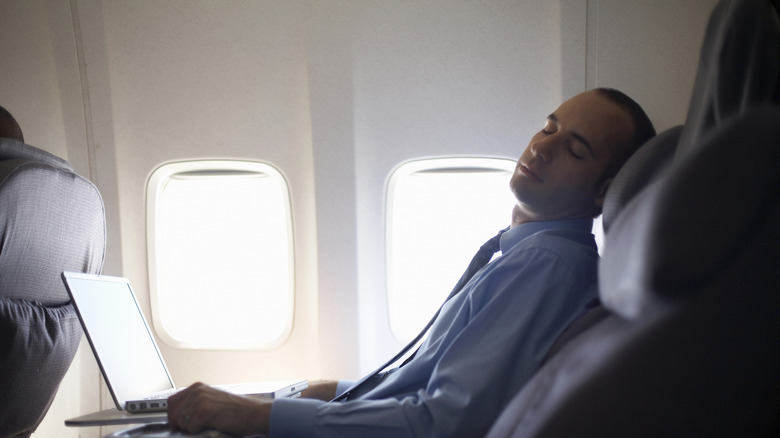 Man resting on an airplane with his seat tilted backwards