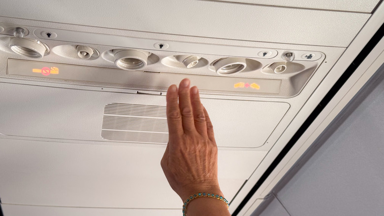 Male hand adjusting air vent in airplane cabin