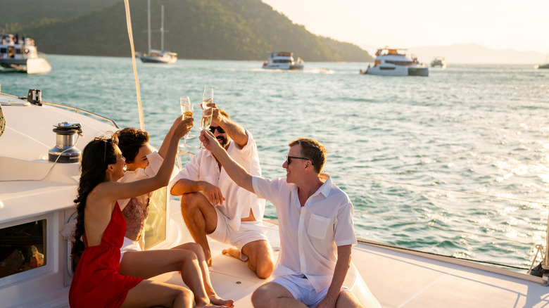 Group of friends on a yacht holding glasses for a toast