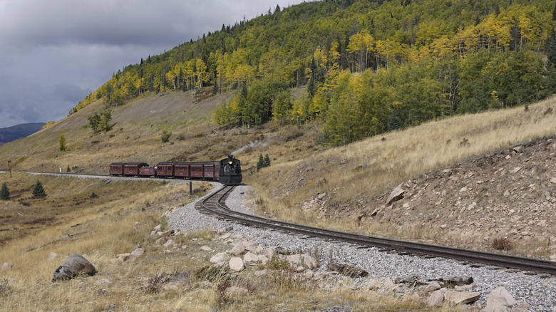 The Cumbres and Toltec Railroad passing by mountains.