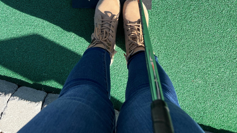 Someone standing in front of the tee on a mini putt putt putting green