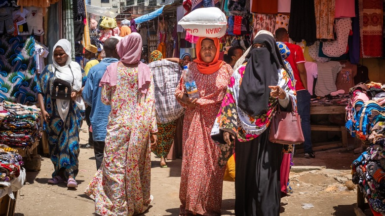 Modestly dressed women and men at a market in Zanzibar