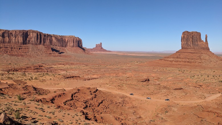 Mitten Butte in Monument Valley with cars driving loop below