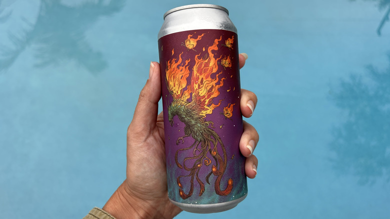 Hand holding a vibrant can of Unseen Creatures, a Miami IPA