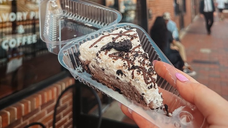 Person holding a piece of pie in front of Pie Bar in Woodstock, Georgia