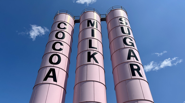 Three pink silos stand high in the air, labeled "Cocoa," "Milk," and "Sugar," as a part of Malley's Chocolates in Cleveland, Ohio
