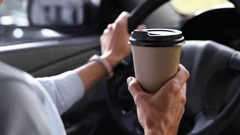 Woman drinking from a disposable coffee cup while driving