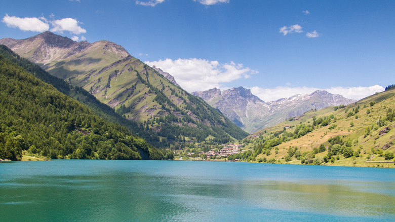 Blue water in lake with village and mountains behind