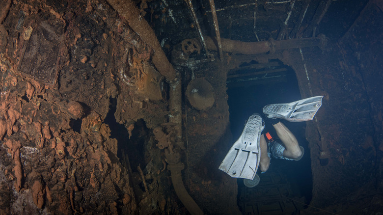 Diver swimming through warship wreckage