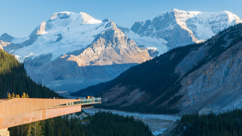 A skywalk platform jutting out above ground, surrounded by mountains