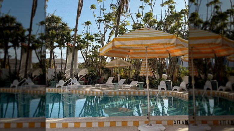 A pool with yellow striped umbrellas at Mello on the Beach in Florida