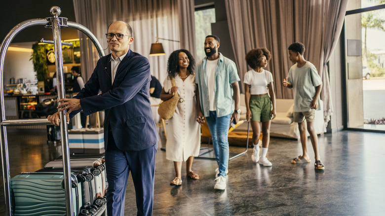Bellhop carrying bags of a family arriving at a luxurious five star hotel