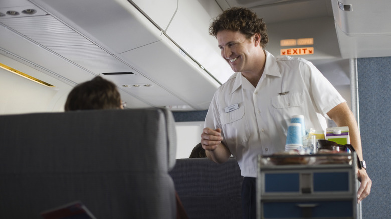 A flight attendant offering beverages to a passenger