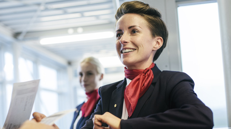 A happy flight attendant checks boarding passes