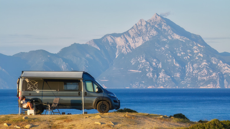 Campervan parked in front of water and mountains
