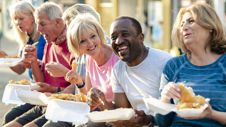 Group of people eating fish fry and smiling