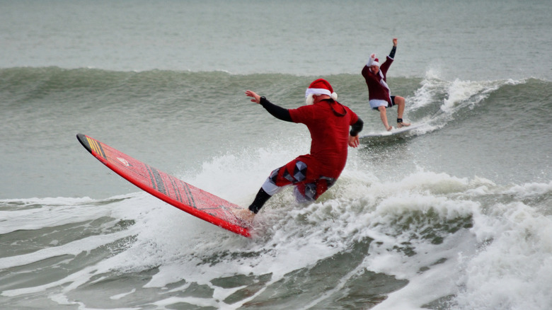 People in Santa outfits surfing in ocean