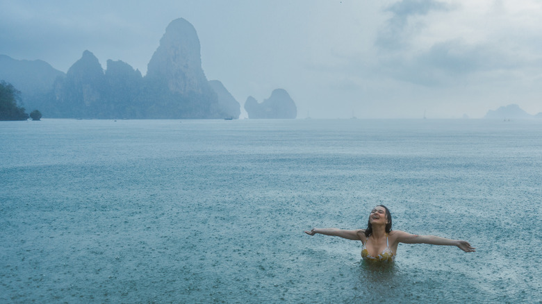 A young woman swimming in the sea under the tropical rain in Thailand.