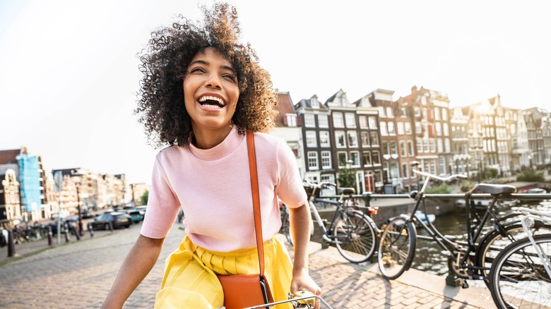 Closeup of woman laughing in Amsterdam with Dutch buildings, bikes, and the Canals of Amsterdam behind her