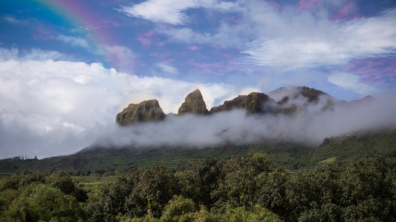 Jagged Kalalea Mountain ridges with clouds and a rainbow