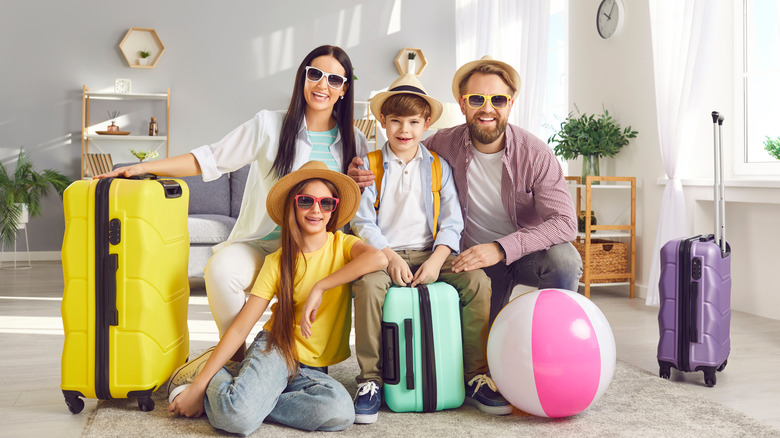 A family of four with suitcases and a beach ball