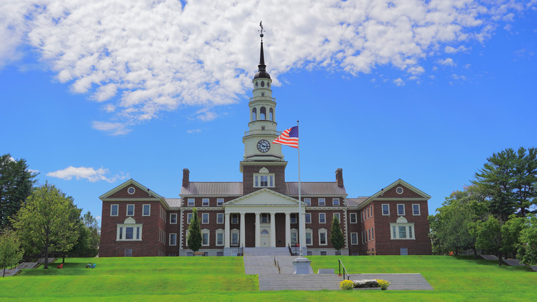 An exterior view of a building on Colby College campus with american flag waving from flagpole