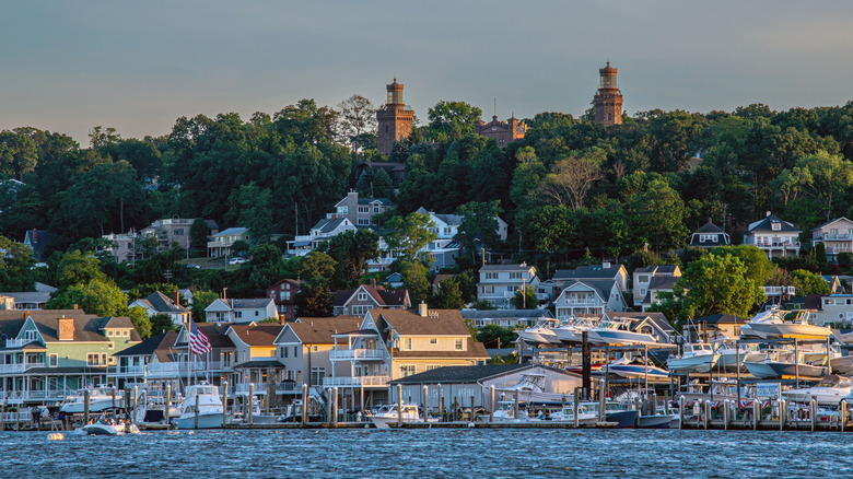 View of Highlands, New Jersey with houses, boats, and two lighthouses surrounded by trees in the background.