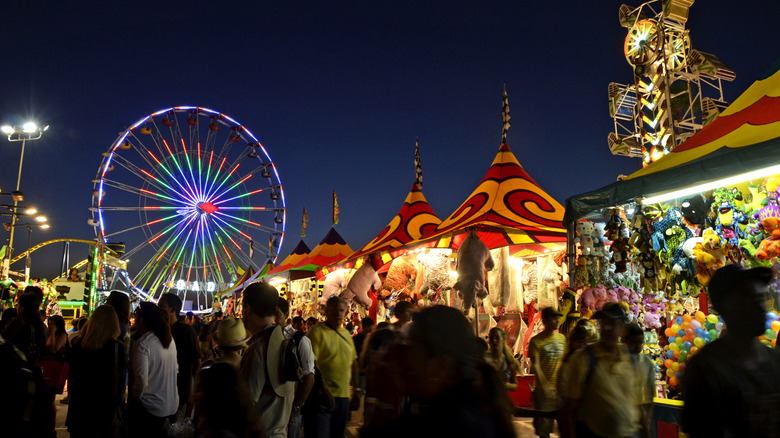 Evening at the San Diego County Fair with a lit Ferris Wheel and game booths on the Del Mar Fairgrounds