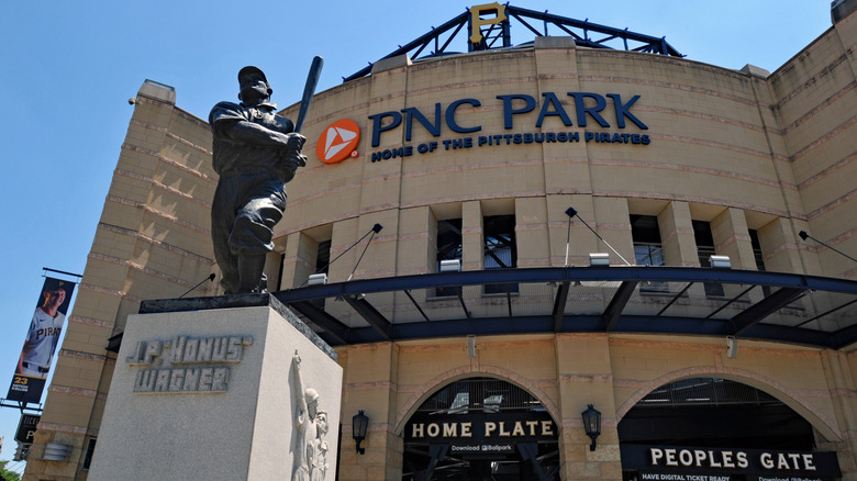Honus Wagner statue outside PNC Park, a large white stone building with a curved front, under a blue sky