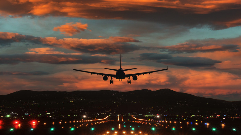 An aircraft prepares to land at sunset