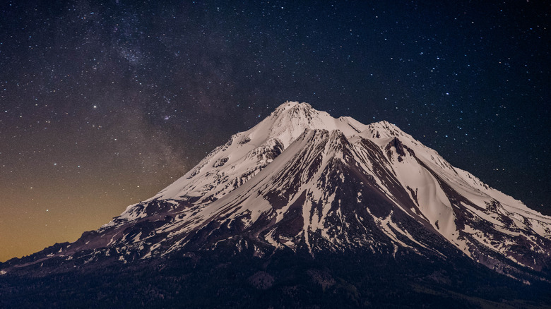 Mount Shasta covered in snow below a starry sky