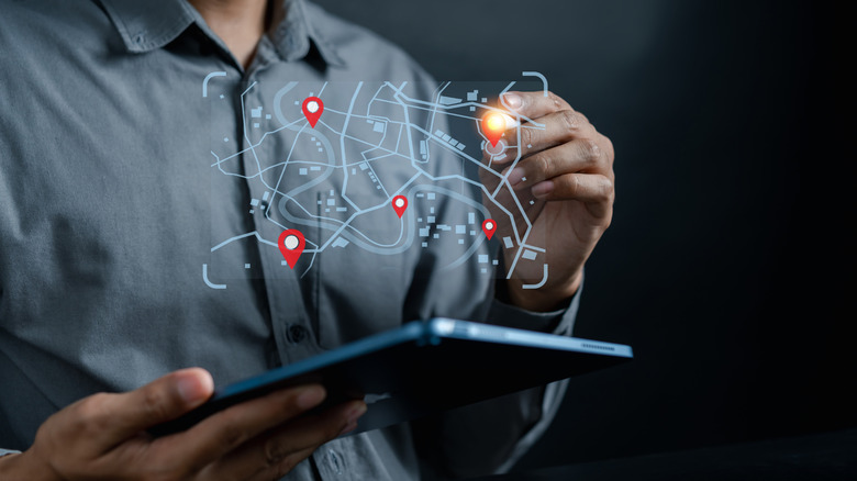 Close-up image of a man in a business shirt using GPS on a tablet to find a route or destination