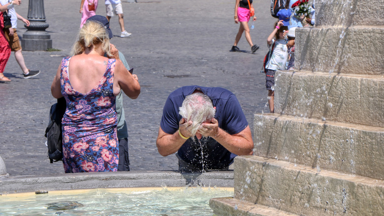 Man splashing water on face at fountain in Rome