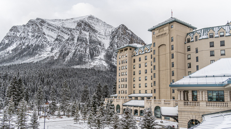 Image of the iconic Fairmont Chateau Lake Louise hotel in Banff National Park, with snowcapped mountains and forests in the background