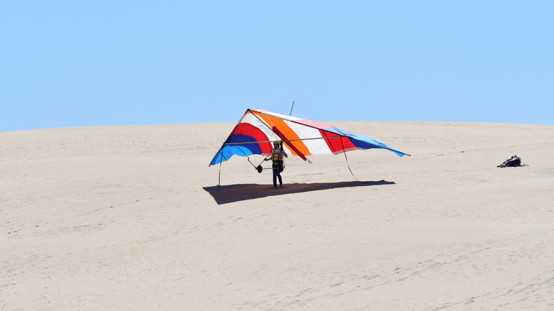 A man carries a hang glider at the famous Kitty Hawk hang gliding school in North Carolina's Jockey's Ridge State Park