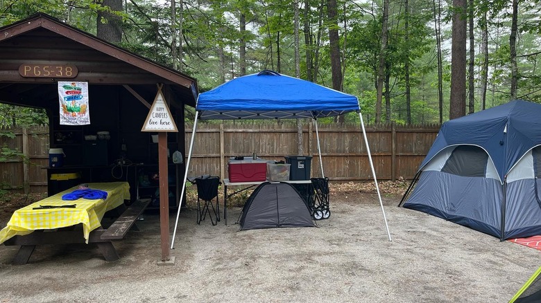 An outdoor kitchen, a pop-up canopy, and a tent at Papoose Pond Family Campground & Cabins, in Maine.