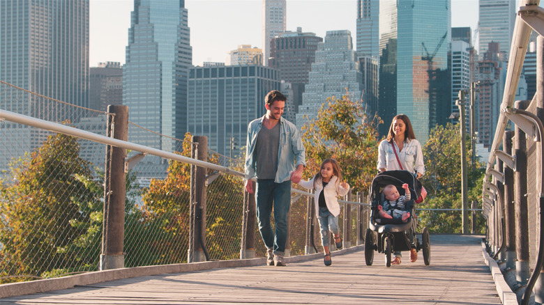 A family smiling and walking across a bridge in New York City