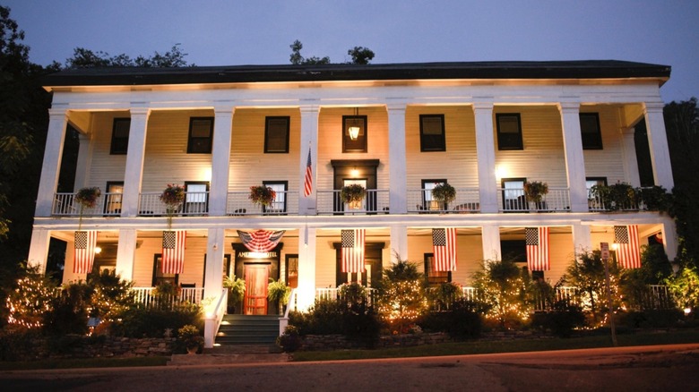 Front view of the American Hotel during the evening with American flags hanging on the front porch.