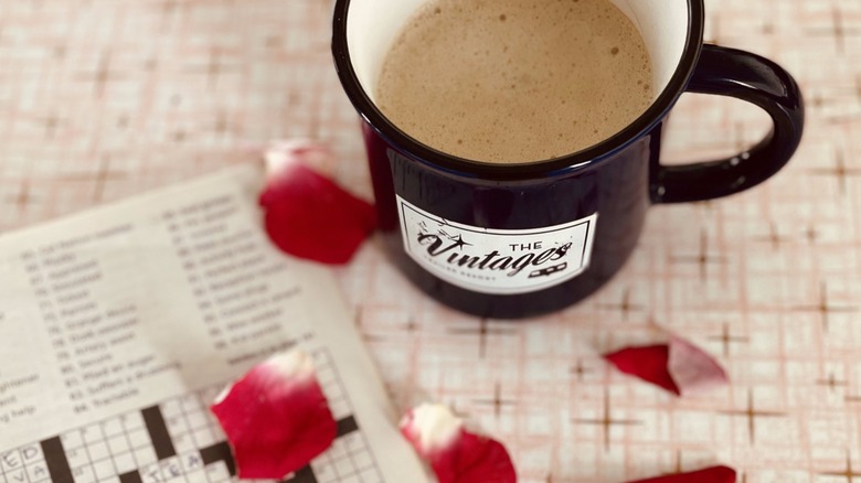 Coffee mug, crosswords, and rose petals on formica table at The Vintages