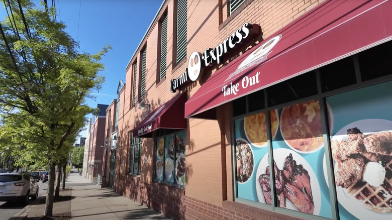 bred brick building with white sign next green trees under blue sky