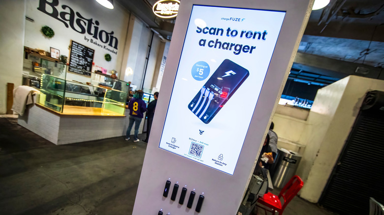 Power charger kiosk with a picture of a mobile phone and the words "scan to rent a charger" inside a cafe