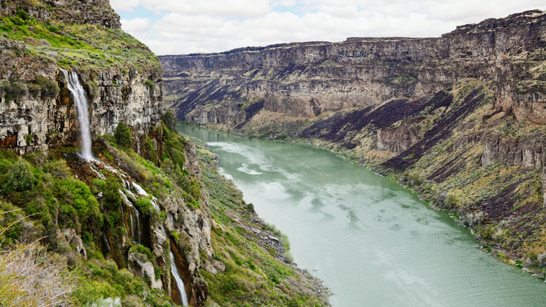 Waterfall surrounded by greenery cascades down into the turquoise Snake River, Idaho