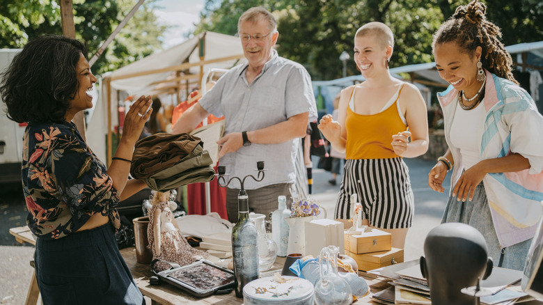 Four people browsing at an open air flea market booth