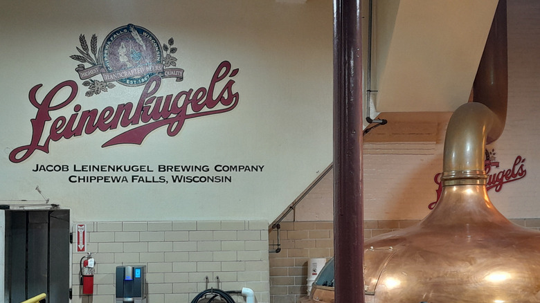 Inside Leinenkugel's Brewery with a sign on the wall and a copper vat.