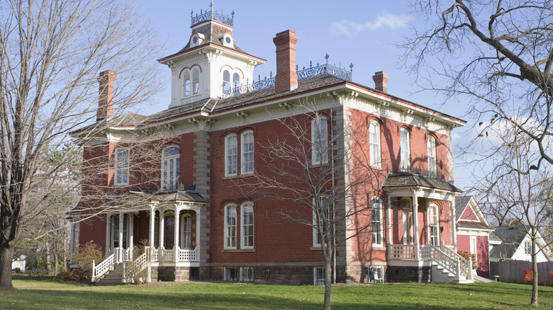 A historic mansion in Chippewa Falls with Victorian-era architecture and a green lawn.