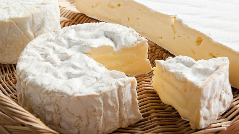 A rind of white brie cheese with a piece cut out of it